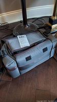 Another angle of gray camera bag closed with a note on top indicating content and lot number.