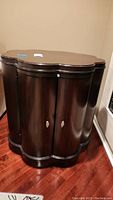 Side view of dark wooden side cabinet with curved design and visible handles on double doors.