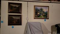 Overview of three framed paintings mounted on wall