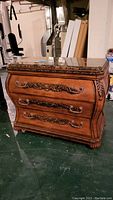 Front three-quarter view of bombe chest showing overall shape, carved trim, and drawer fronts
