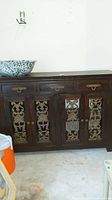Front view of the wooden buffet showing the three drawers at top and four doors with intricate metal decorative panels.