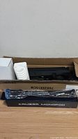 Box containing two black lighting shades, tripod in box marked 'camera monopod' and white packaging material visible