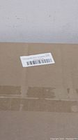 Close-up of brown cardboard box packaging with a shipping label attached. The box is taped and unmarked otherwise.