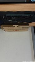 Full-size black keyboard inside a box on a desk