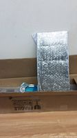 Shower panel wrapped in bubble wrap inside a brown cardboard box.