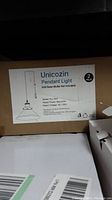 Unicozin Pendant Light 2-pack box label with model RJ-1002, E26 base, 60W, 120V AC, bulbs not included.