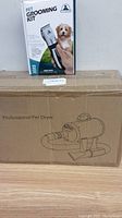 Photo showing boxed professional pet dryer with line drawing on box and boxed pet grooming kit with image of a dog on the cover