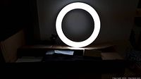 Ring light illuminated in a dark setting showing circular white light.