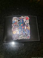 Front view of black leather wallet featuring embossed colorful Norval Morrisseau artwork of "Man into Thunderbird".