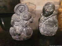 Front view of both soapstone Eskimo figure carvings, showing detailed facial features and fur-lined parkas