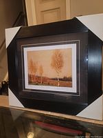 Full view of framed and matted fine art print showing the artwork titled 'Northern Birches' by Tom Thomson in a dark wood frame with protective corners on.