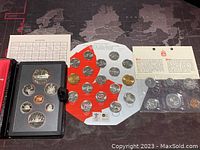 Full view of 1974 proof-like set in black case along with 1984 Silver Dollar set and 2010 Olympic coin set on maple leaf background.
