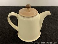 Side view of cream-colored ceramic Denby tea pot with beige lid and knob.