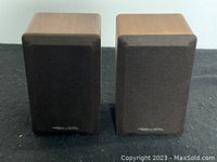 Front view of two Realistic Minimus 7 small wooden bookshelf speakers with brown fabric grilles.