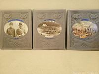 Front covers of three gray hardcover Civil War books with embossed U.S. and C.S. logos, each featuring an oval image depicting a battle scene or soldiers, arranged side by side.
