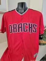 Front view of red Arizona Diamondbacks jersey with stitched DBACKS lettering and button closure.