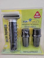 Packaged FURminator DeShedding Vac Tool including two universal vacuum cleaner adapters, black and silver in color, sealed in plastic blister pack with branded yellow card