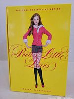 Front cover of the Pretty Little Liars box set showing a blonde doll-like illustration on a yellow background with the title and author name.