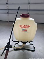 Front view of Chapin Pro Series backpack sprayer showing tank, lid, and spray wand attached to hose and handle on metal frame