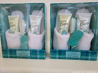 Front view of both boxed sets, showing slippers, lotion tubes, nail brushes, pumice stones clearly inside packaging.