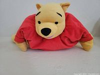 Front view of Winnie the Pooh plush pillow pet showing yellow face, red shirt, and soft fabric.