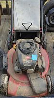 Front angled view of Toro lawn mower showing engine top, deck, and part of handlebar with grass bag visible.