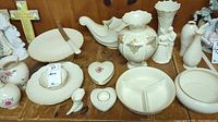 Photo of various Lenox porcelain items on wooden surface, including cake stand with knife, cornucopias, heart-shaped boxes, and several vases.