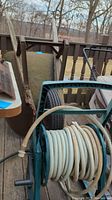 Shows wheelbarrow with moss and single tire and garden hose on reel