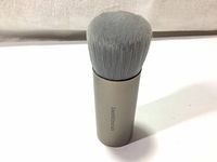 Front view of BareMinerals Seamless Buffing Brush with gray tightly packed charcoal bristles and silver handle.