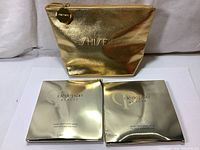 Two gold foil packets of Cle De Peau Beaute Intensive Brightening Masks and a gold cosmetic pouch with Shiseido branding.