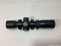 Side angle view of black Excalibur Tact 100 crossbow scope showing adjustment knobs, matte finish, and mounting rings.