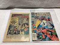 Shows both comic books side by side, Superman and Batman on left, Transformers on right.