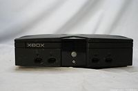 Front view of the black Xbox console showing four controller ports, memory card slots and power button.