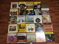 Photo showing 25 vintage LP records laid out in a grid on a hardwood floor, featuring covers with classical, opera, jazz and various artists.