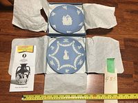 Two brand new Wedgewood 7 inch blue Jasperware plates in original packaging with tissue paper, including informational leaflet and label.