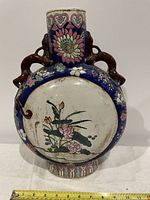 Front side of vase showing lotus flowers, cobalt blue border, and two brown branch-like handles.