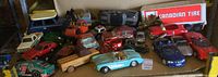 Overview of the collection showing assorted antique and vintage toy cars and trucks on cardboard, featuring a red car, blue sports car, toy crane, and Canadian Tire trailer toy.