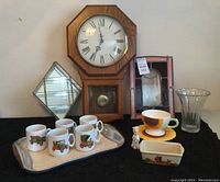 Overall view showing clock, serving tray with five coffee mugs, sunflower cup and plate, stained glass panel, glass curio shelf, glass vase, ceramic butter dish