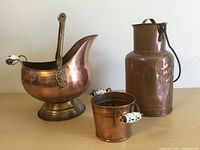 Photo showing all three copper items on a wooden surface: the urn, canister, and planter pot.