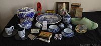 Overview of entire lot showing various Delft Blue pottery items, wooden clog decoration, green shoe planter, vintage boxes and candles.