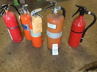 Full lot of five fire extinguishers arranged on floor, showing various colors and sizes.