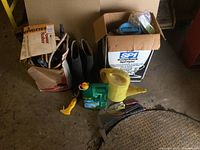 Lot items displayed on garage floor including backpack sprayer, power roller box, boots, watering can, and garden tools
