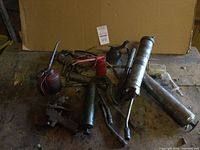 Overview of all items on wooden surface including grease guns, oil cans, and a wrench