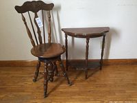 Photo showing the vintage piano stool with back and claw feet next to the half moon console table against the wall on wooden flooring.