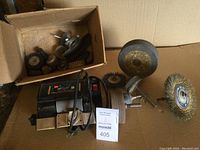 Photo showing WEN electric wet wheel sharpener with power cord and mounted grinding wheel, alongside a box containing various small grinding and polishing wheels.