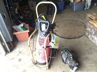Red Coleman power washer with yellow handle and a smaller gray power washer on the floor, showing overall lot contents.