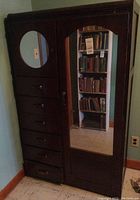 Front view of vintage chifferobe wardrobe showing six drawers on left, full-length mirror door on right, and circular mirror inset on the upper left door