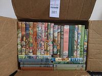Top-down photo of box filled with vintage children's hardcover books with colorful spines and illustrated covers.