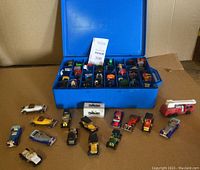Blue plastic storage case open showing various vintage Hot Wheels and toy cars inside, multiple compartments visible