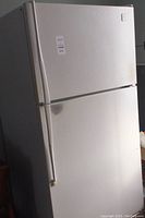 Front view of white Whirlpool refrigerator with top freezer and bottom fridge door.